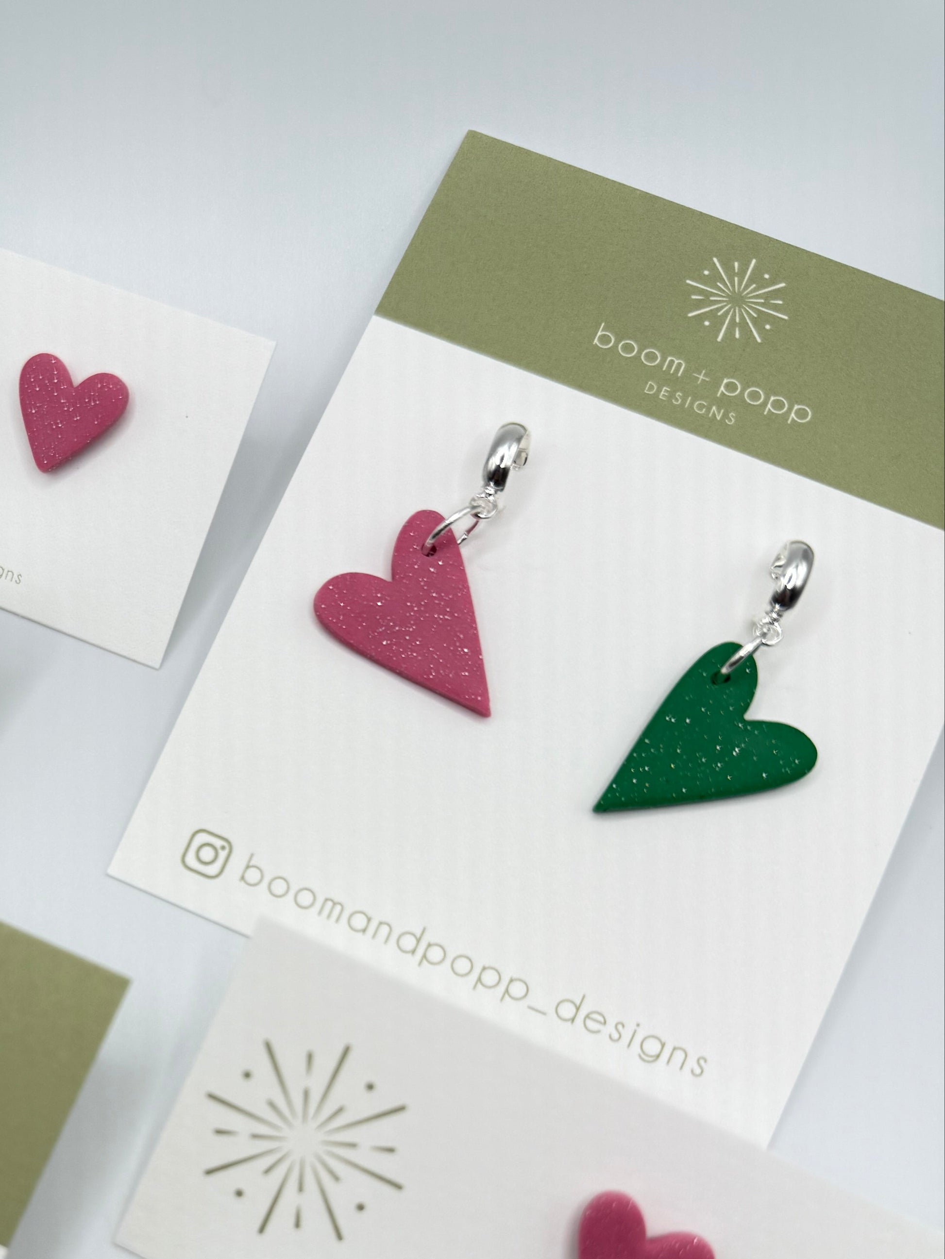 Heart-shaped earrings on branded cards with a light gray background